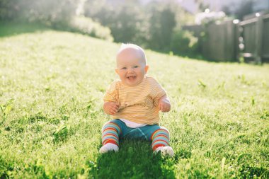 Bebek doğa güneş ışığı altında. Yaz yeşil çim sevimli küçük kız. Çocukluk resmini. Anne ve çocuk açık havada aktivitesiyle. Çayır parkta güzel mutlu çocuk oturur.