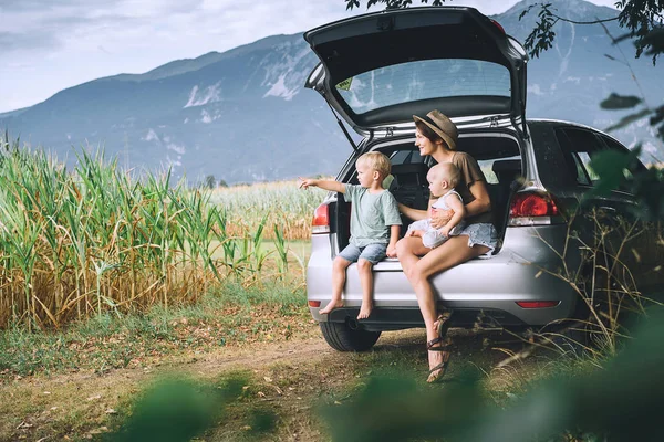 Bir açık araba bagajında oturan ve doğa ve kırsal çocuk ve anneleri. Aile içinde bir yolculuk. Mısır alanları ve dağlar Lake Bled, Slovenya, Europe yakın. Seyahat, yaşam kavramı.