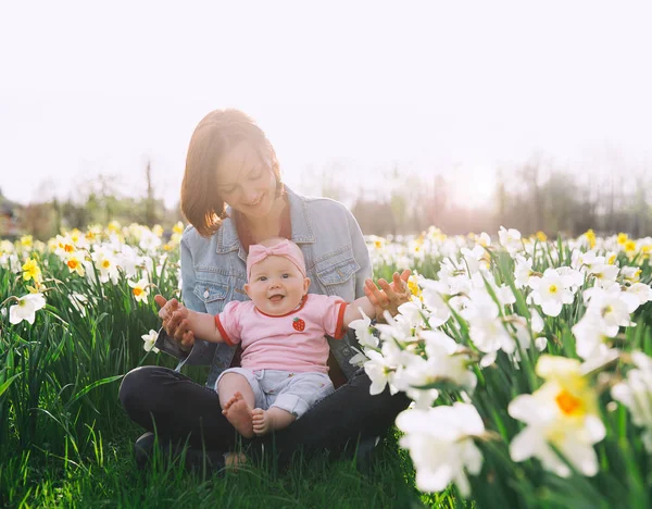 Moeder en baby meisje in voorjaar park onder de bloesem veld — Stockfoto