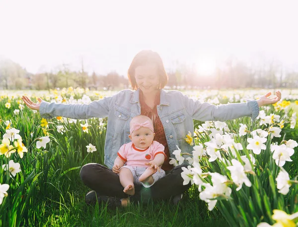 Moeder en baby meisje in voorjaar park onder de bloesem veld — Stockfoto