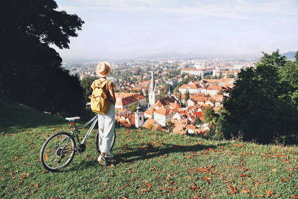 Девушка с рюкзаком и велосипедом исследует Любляну. Словения — стоковое фото