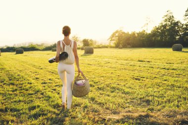 Yoga ilhamının doğadaki görüntüsü. Yoga minderli genç kadın dışarıda yoga yapmaya hazırlanıyor. İnce, güçlü, beyaz elbiseli güzel bir kadın. Sağlıklı ve bilinçli yaşam tarzları.
