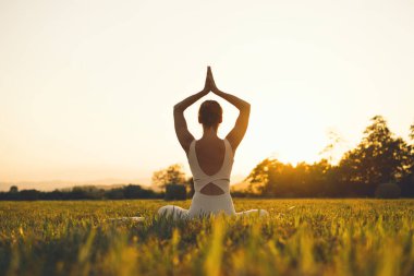 Doğada yoga yapan genç bir kadın. Kız dışarıda meditasyon yapıyor. İnce, güçlü ve esnek vücutlu bir kadın. Sağlıklı yaşam tarzları. Canlılık, sakinlik, rahatlama, farkındalık, zen enerjisi kavramı.