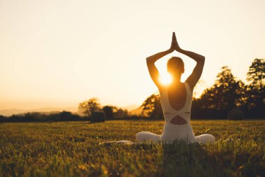 Doğada yoga yapan genç bir kadın. Kız dışarıda meditasyon yapıyor. İnce, güçlü ve esnek vücutlu bir kadın. Sağlıklı yaşam tarzları. Canlılık, sakinlik, rahatlama, farkındalık, zen enerjisi kavramı.