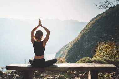 Doğada yoga yapan bir kadın. Genç kadın dağların arka planında meditasyon yapıyor. Sağlıklı yaşam tarzları, sakinlik, rahatlama, farkındalık, canlılık enerjisi..