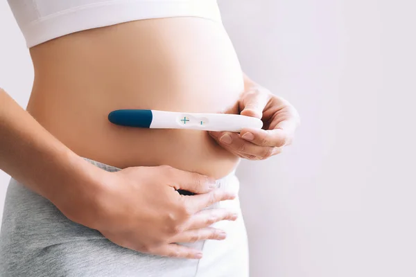 Młoda Kobieta Trzymająca Test Ciążowy Rękach Przytulająca Brzuch Koncepcja Ciąży — Zdjęcie stockowe