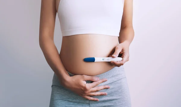 Młoda Kobieta Trzymająca Test Ciążowy Rękach Przytulająca Brzuch Koncepcja Ciąży — Zdjęcie stockowe