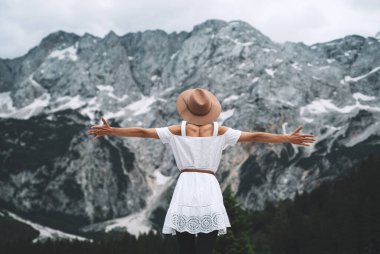 Güzel genç bir kadın dağların arka planında duruyor. Yürüyüşçü kız Alpler 'den ve doğanın güzelliğinden esinlenmiştir. Slovenya, Avrupa 'ya macera seyahati. Özgürlük, Eğlence Faaliyetleri Yaşam tarzı