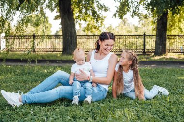 kızları ile anne parkta çim üzerinde oturan ve oynarken
