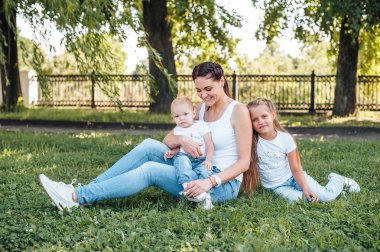 kızları ile anne parkta çim üzerinde oturan ve oynarken