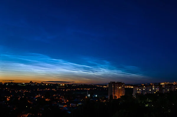 Noctilucent clouds during night time, city scape. Highest clouds in the Earths atmosphere, beautiful sky phenomenon.