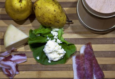 Homemade cheese, cayenne and prosciutto on a wooden board