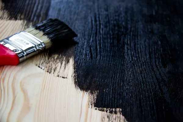 Natural wooden pine board painted in dark color. Paint brush on a painted board. Beautiful wood background