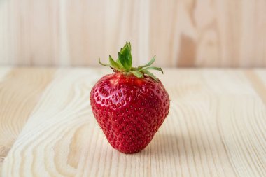 Ahşap arka planda çilek standı. Ahşap arka planda kırmızı taze bir çilek..