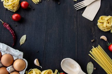 Yemek pişirme arka planında mesaj için boş yer var. Spagetti, domates, yumurta, sarımsak, ahşap arka planda defne yaprağı. Fotokopi alanı ile yemek yapmak için gerekli malzemeler. Tasarım için üst görünüm