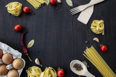 Yemek pişirme arka planında mesaj için boş yer var. Spagetti, domates, yumurta, sarımsak, ahşap arka planda defne yaprağı. Fotokopi alanı ile yemek yapmak için gerekli malzemeler. Tasarım için üst görünüm