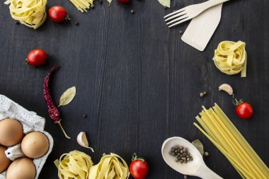 Yemek pişirme arka planında mesaj için boş yer var. Spagetti, domates, yumurta, sarımsak, ahşap arka planda defne yaprağı. Fotokopi alanı ile yemek yapmak için gerekli malzemeler. Tasarım için üst görünüm