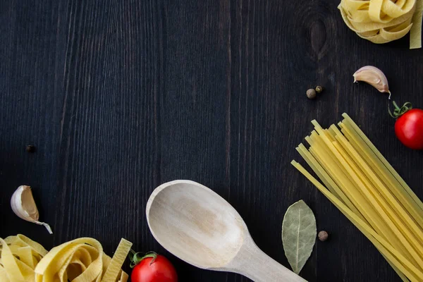 Yemek pişirme arka planında mesaj için boş yer var. Spagetti, domates, yumurta, sarımsak, ahşap arka planda defne yaprağı. Fotokopi alanı ile yemek yapmak için gerekli malzemeler. Tasarım için üst görünüm