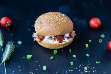 Kızarmış domuz dilimli lezzetli burger soslu lahana, konserve salatalık ve ahşap zemin üzerinde ketçap.