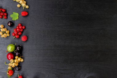 Fotokopi alanı olan böğürtlenli ahşap arka plan. Çerçeve kenarı karışık böğürtlenlerden yapılmış düz bir bileşim. Ahududu, kiraz, Bektaşi üzümü, Koyu ahşap arka planda çilek