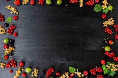 Fotokopi alanı olan böğürtlenli ahşap arka plan. Çerçeve kenarı karışık böğürtlenlerden yapılmış düz bir bileşim. Ahududu, kiraz, Bektaşi üzümü, Koyu ahşap arka planda çilek