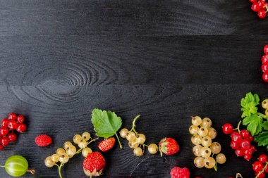 Fotokopi alanı olan böğürtlenli ahşap arka plan. Çerçeve kenarı karışık böğürtlenlerden yapılmış düz bir bileşim. Ahududu, kiraz, Bektaşi üzümü, Koyu ahşap arka planda çilek