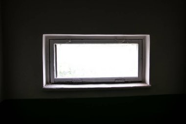 Karanlık, kasvetli bir odadan kirli bir pencere ve dışarıdan bir ışık. Kirli camları, karanlık duvarları ve dışarıdan gelen ışığı olan eski püskü bir pencere.