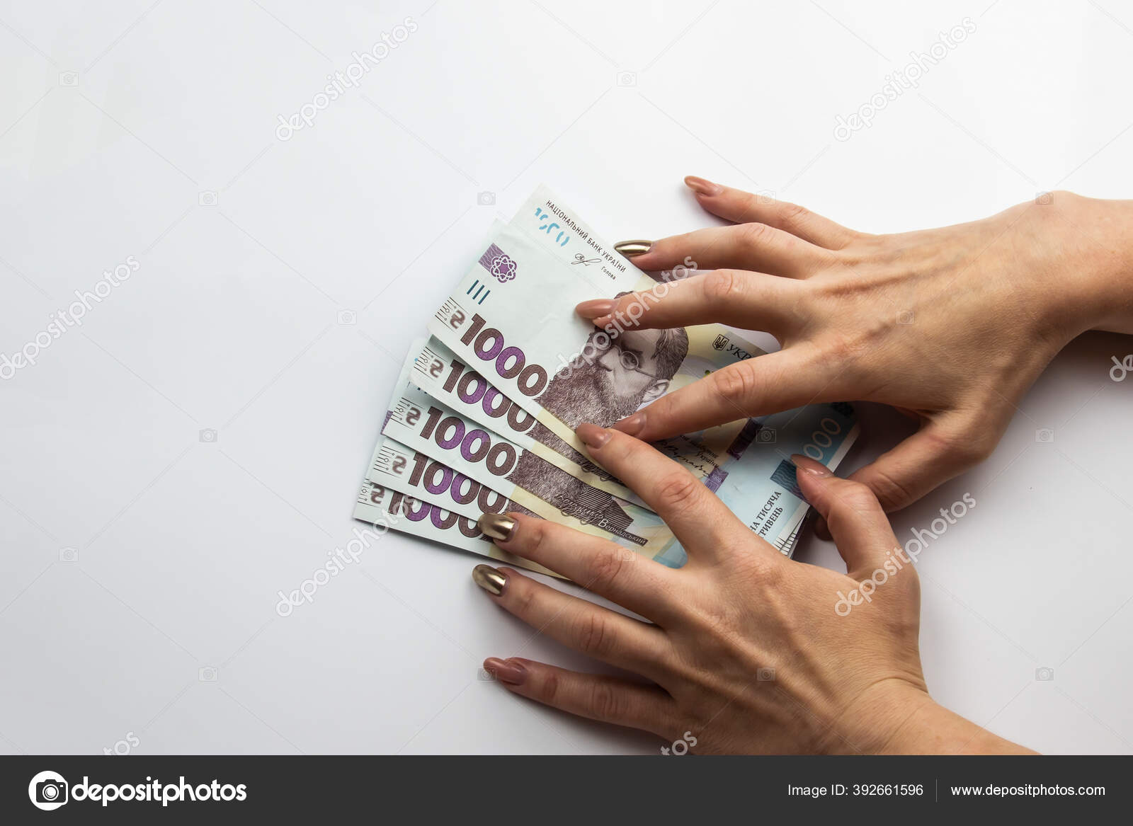 女性的手牵着5000格里夫尼亚乌克兰货币妇女的手相对于白色背景五千格里夫尼亚和一千格里夫尼亚五张钞票