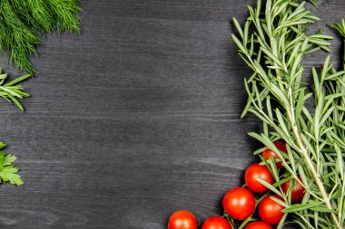 Kiraz domatesli, dereotlu, maydanozlu, ahşap kaplamalı biberiyeli kompozisyon. Yemek pişirme arka planında mesaj için boş yer var. Kopyalama alanı olan üst görünüm