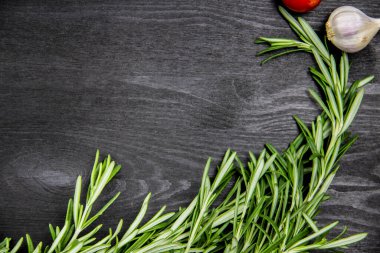 Kiraz domatesli kompozisyon, biberiye, koyu ahşap arka planda sarımsak. Yemek pişirme arka planında mesaj için boş yer var. Kopyalama alanı olan üst görünüm