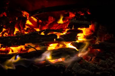 Siyah arka planda ateş olan kırmızı kömürler. Yanan kömür ve ateşte odun. Isınmak ve ısınmak için odun yakıyorum. Sıcak kırmızı, turuncu renkli közler. Soyut arkaplan. Doku ateş közleri