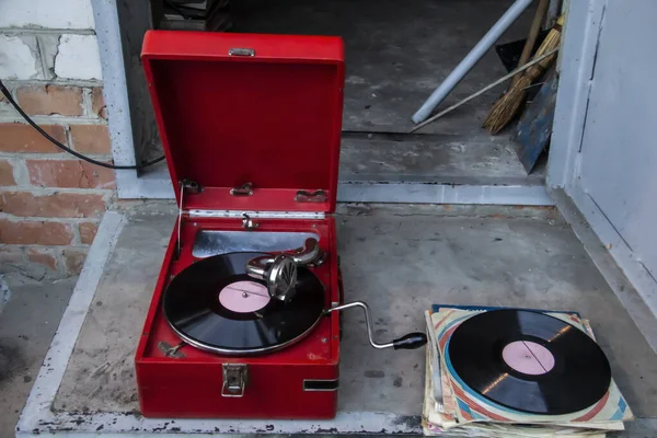 Old red vintage record player with vinyl record outside house. Old school style.