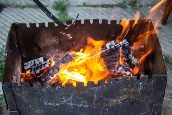 Mangal mangal hazırlığı ve binanın dışında başıboş ateş. Yakacak odun yakar