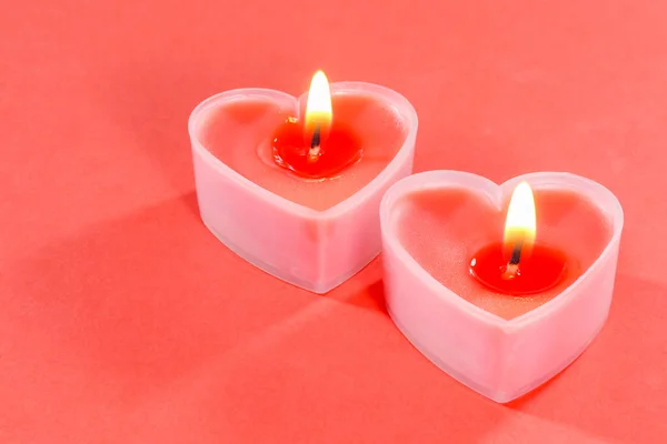 Sevgililer Günü için kırmızı zemin üzerinde kalp şeklinde pembe mumlar. 