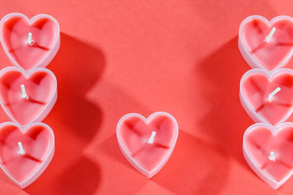 Velas rosadas en forma de corazón sobre fondo rojo para el día de San Valentín — Foto de Stock