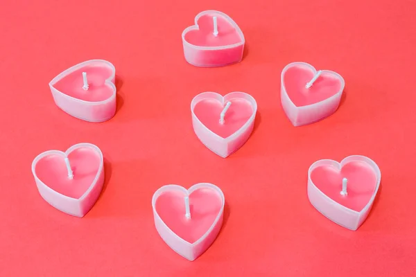 Sevgililer Günü için kırmızı zemin üzerinde kalp şeklinde pembe mumlar. — Stok fotoğraf