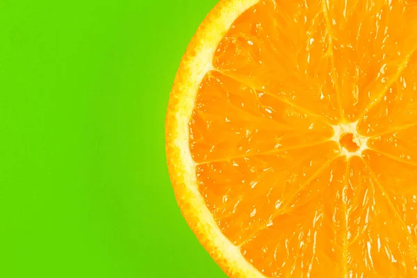 Rebanada de naranja en una macro de fondo verde. lugar para la etiqueta — Foto de Stock