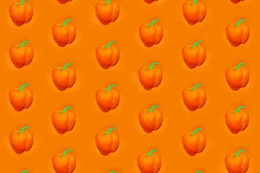 Turuncu arka planda turuncu dolmalık biberli renkli sebze deseni. Dolmalık biber deseni. Yukarıdan görünüm