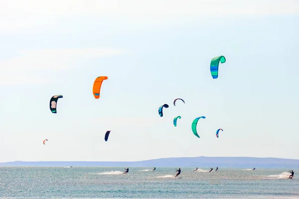 Een kitesurfer die surft op het gladde azuurblauwe water. recreatieve sport. Een man rijdt met een vlieger in het zeewater. Extreme sport. Spring maar. — Stockfoto