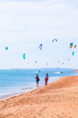 Uçurtma sörfçüsü pürüzsüz gök mavisi sularda sörf yapıyor. Eğlence sporu. Bir adam deniz suyunda uçurtma sörfü yapıyor. Ekstrem. Atla
