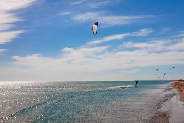 Um kitesurfista surfando na água azul suave. desporto recreativo. Um homem monta um Kiteboarding na água do mar. desporto extremo. Salta. — Fotografia de Stock
