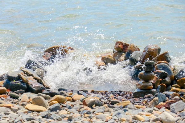 Galets et pierres sur la plage. vagues et éclaboussures sur le rivage — Photo