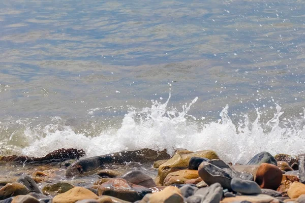 Galets et pierres sur la plage. vagues et éclaboussures sur le rivage — Photo