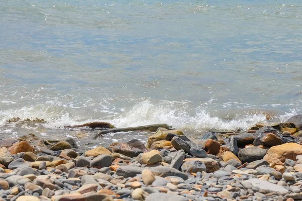 Galets et pierres sur la plage. vagues et éclaboussures sur le rivage — Photo