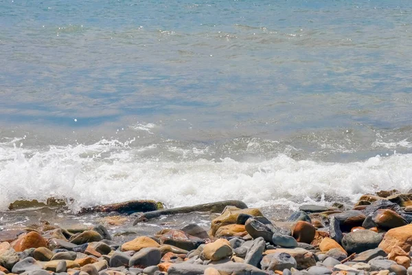 Galets et pierres sur la plage. vagues et éclaboussures sur le rivage — Photo