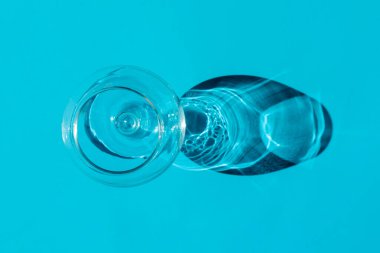 Düz arkaplanda sert gölgesi olan bir cam. Yukarıdan manzara. Desen için boş