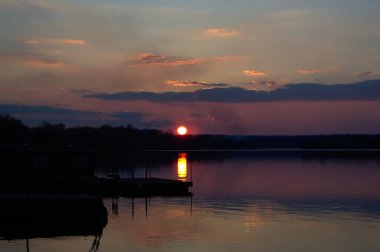 Eski iskeleye yakın göl kıyısında altın saat boyunca muhteşem pembe canlı günbatımı.
