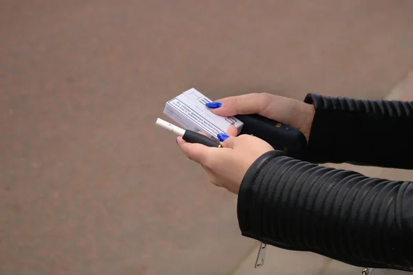 Londra, Ingiltere, Haziran 2019. Tütün sistemi Iqos. Elinde e-sigara tutan kadın. Elektronik sigara ile kadın el, sokak arka planda teknoloji Sigara. 