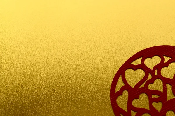 Shiny yellow metallic gold leaf foil texture background with carved red hearts. Love card