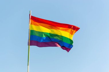 Parlak gökkuşağı gay bayrağı mavi gökyüzü arka plan karşı rüzgarsal sallayarak